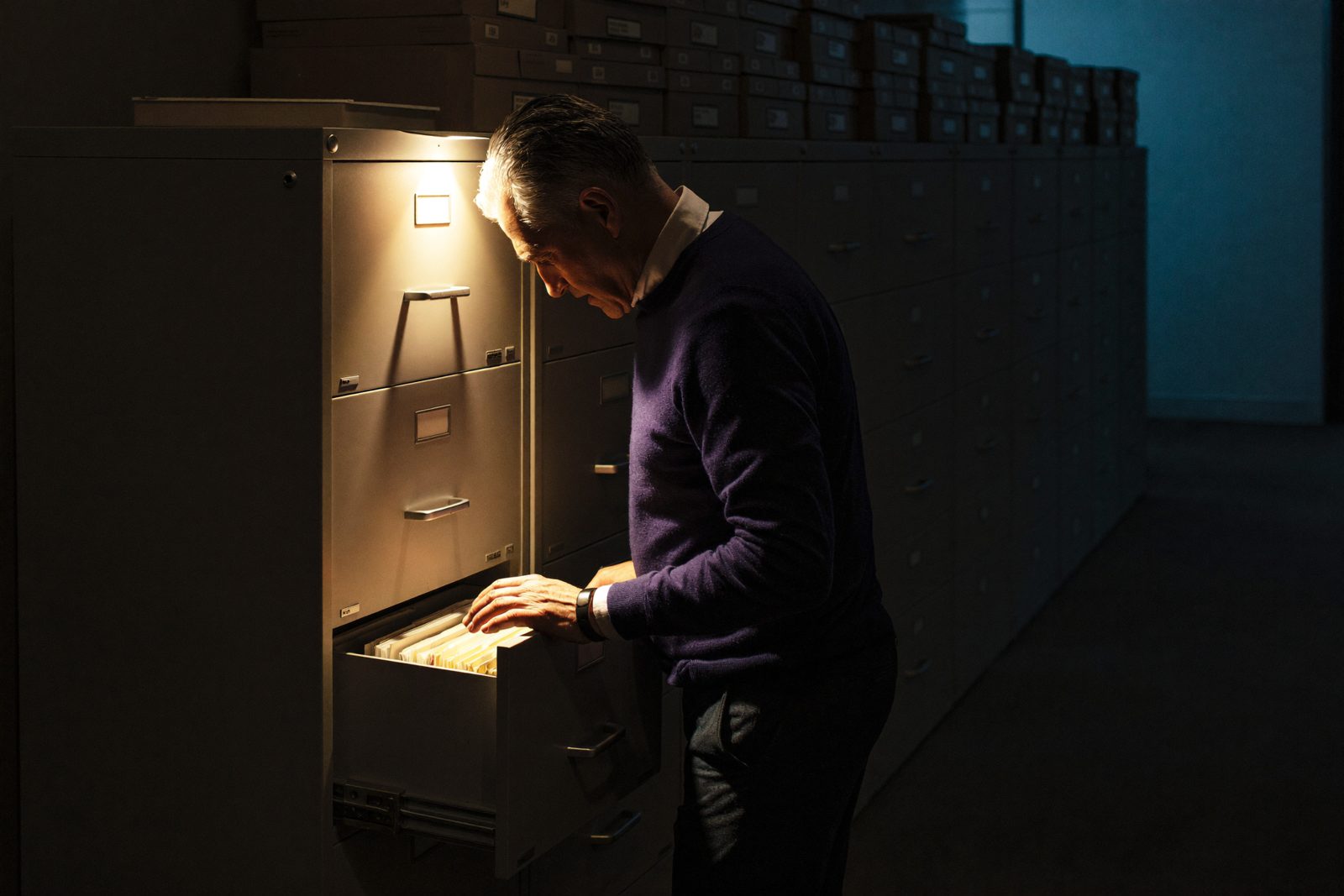 A dim records room, one drawer open and lit.